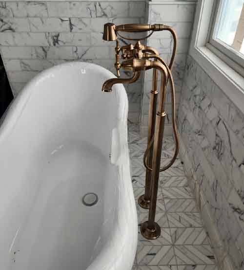 Bathroom remodeling project featuring freestanding tub with bronze faucet and marble tile walls in South Jersey home.