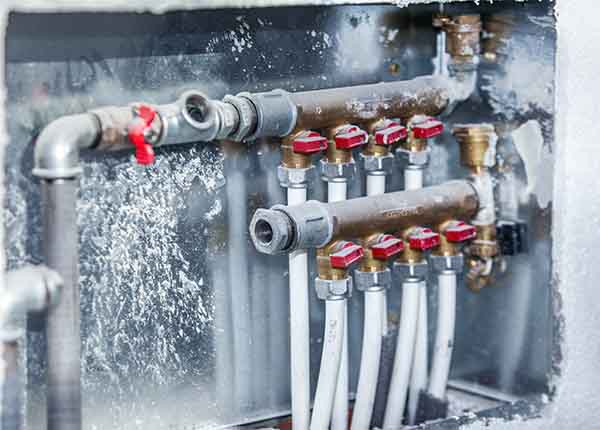 Frozen plumbing manifold with multiple water lines and shut-off valves serviced by L.F. Fenimore Plumbing and HVAC in South Jersey